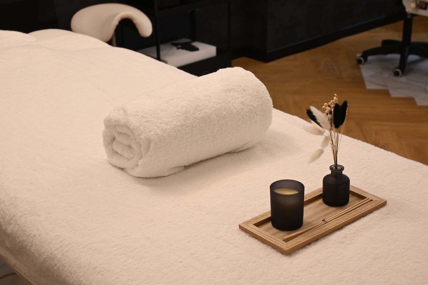 Massageliege mit gerolltem Handtuch und Kerze in einem ruhigen Spa-Raum